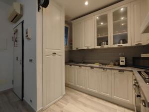a kitchen with white cabinets and a refrigerator at Appartamento al parco con parcheggio gratuito in Orbetello