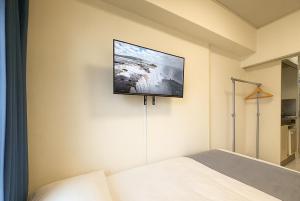 a bedroom with a bed and a tv on the wall at Kurarisu Hakata クラリス博多 in Fukuoka