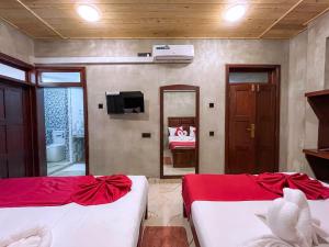 a room with two beds and a tv and a mirror at Ella Tea Heaven Resort in Ella