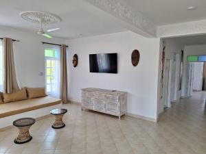 a living room with a couch and a tv on a wall at Nyumba Maua B&B in Watamu