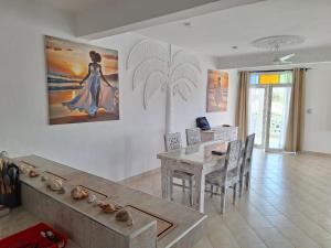 a dining room with a table and a painting on the wall at Nyumba Maua B&B in Watamu