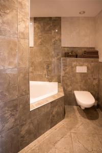 een badkamer met een bad en een toilet bij Villa het Bascour in Vierlingsbeek