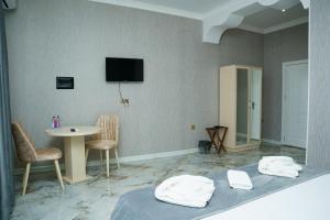 a room with a bed and a table and a tv at Kolizey Hotel Spa Ganja in Ganja