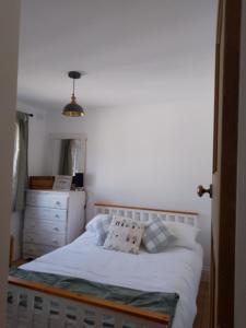 a bed with white sheets and pillows in a bedroom at Small cottage in Stratton, Bude in Stratton