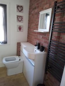 a bathroom with a white sink and a brick wall at Small cottage in Stratton, Bude in Stratton
