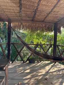 a hammock on a porch with a thatched roof at Campo de Heliantos in Santarém