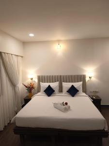 a bedroom with a large white bed with blue pillows at Ello Hotels in Bengaluru