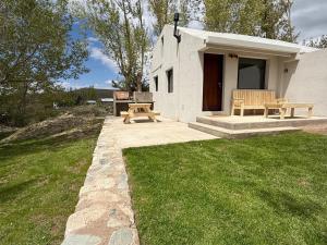a small white house with a picnic table and benches at Cabañas boutique Huella Andina in Potrerillos