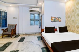 a hotel room with two beds and a chair at Super Hotel O Shalimar Railway Junction Formerly Tanima Villa 2 in Howrah
