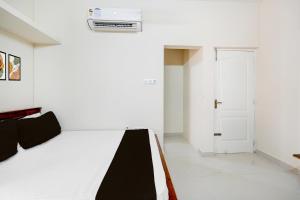 um quarto branco com uma cama e uma porta em Super Collection O Sholinganallur Chennai Formerly Nimalan Residenc em Chennai