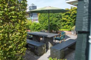 a table and bench with an umbrella and a table and chairs at Hotel Beemster in Middenbeemster
