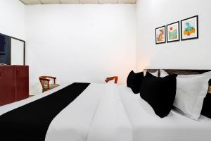 um quarto com uma cama com almofadas pretas e brancas em Super Hotel O Dehradun Central Railway Junction Formerly Bhagwan Guest House em Dehradun