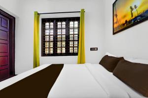 a bedroom with a white bed and a window at Hotel O Kazhakuttam Railway Station Formerly Graceful Stay in Trivandrum