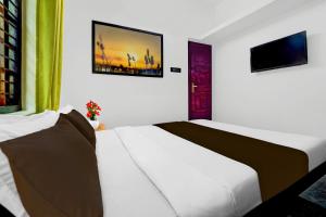 a bedroom with a white bed and a tv at Hotel O Kazhakuttam Railway Station Formerly Graceful Stay in Trivandrum +22 photos