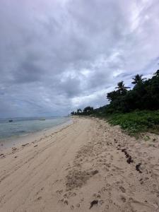 une plage avec des empreintes de pas dans le sable et l'océan dans l'établissement Subangan little Hawaii,6 Burgos Central location, à Burgos