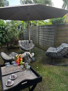 une table avec deux chaises et un parasol dans l'établissement Maison de Vacances à St Anne Martinique, à Sainte-Anne