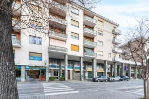 a large white building with cars parked in front of it at Incantevole Appartamento in centro ad Alba in Alba