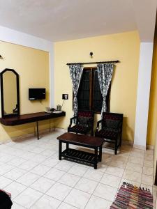 a living room with two chairs and a table and a mirror at Aksha Inn in Madikeri