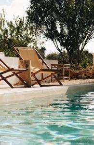 a chair and a table next to a swimming pool at Boutique B&B Villa Gufo in Ostuni