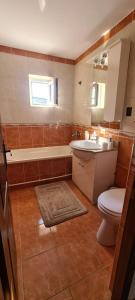 a bathroom with a toilet and a sink and a tub at Apartament in Rădăuţi