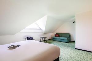 a bedroom with a bed and a green couch at ibis Styles Chartres Sud Barjouville in Chartres