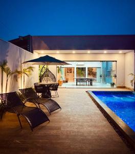 une piscine avec une table, des chaises et un parasol dans l'établissement Espaço LUHNA - Piscina - AR - Sauna Privativa, à Limeira