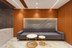 a living room with a couch and two stools at Hotel Rajshree Suites in Ujjain
