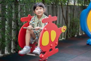 バンコクにあるMaitria Hotel Rama 9 Bangkok - A Chatrium Collectionの幼い子供が遊具に座っている