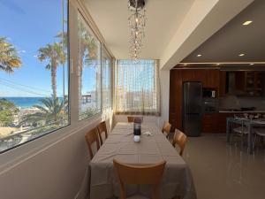 a dining room with a table and some windows at Anna's Seaside Apartment - In front of the beach in Kos Town