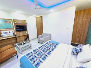 a bedroom with a bed and a chair and a television at Hotel SAROS SUITES Near Delhi AIRPORT By GROSS GROUP in New Delhi