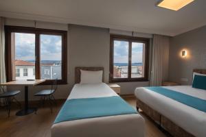 a hotel room with two beds and a desk and windows at Sur Hotel Sultanahmet in Istanbul