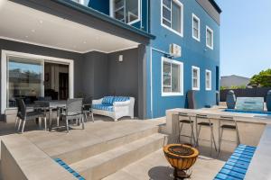 a patio with a table and chairs and a blue building at 51 Dolphin Drive in Cape Town