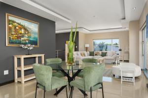 a dining room with a glass table and green chairs at 51 Dolphin Drive in Cape Town