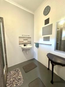 a bathroom with a sink and a clock on the wall at Rus n Bietjie Guest House in Loxton