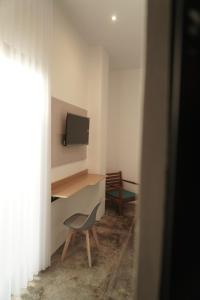 een kamer met een bureau, een stoel en een televisie bij Manta Rooms in Sentool +17 foto's