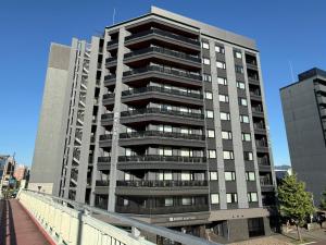 un edificio de apartamentos alto con un puente delante de él en KIORI Exec Gojo, en Kioto
