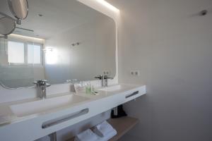 Un baño con lavabo y un espejo grande. en MIM Mallorca Member of Melia Collection, en Sa Coma