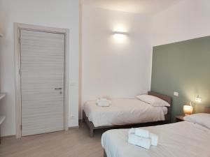 a bedroom with two beds and a door with towels at Casa Nanni in Genova