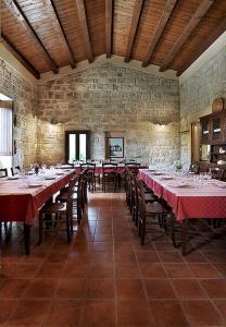 uma sala de jantar com mesas e cadeiras e uma parede de pedra em Agriturismo Il Melograno em Cannizzara