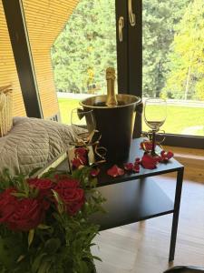 une table avec un seau, un verre à vin et des roses dans l'établissement Honey House Wierchy- prywatna strefa SPA, à Jaszczurowa 65 autres photos