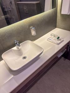 een witte wastafel in een badkamer met een spiegel bij Carom Hotel Manali in Manāli +20 foto's