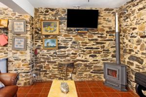 a living room with a stone wall with a stove at T5 com Piscina Casa da Chica in Espiunca