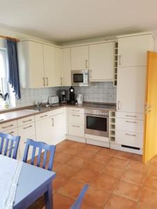 a kitchen with white cabinets and a table and chairs at Haus Kiki in Dornumersiel