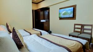 two beds in a room with a tv on the wall at Al Makkah Hotel in Karachi