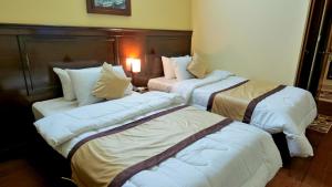 a hotel room with three beds in a room at Al Makkah Hotel in Karachi
