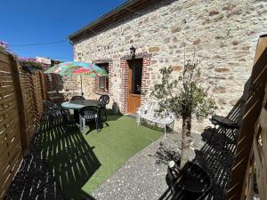a patio with a table and chairs and a brick building at Jolie maisonnette in Barenton-Bugny