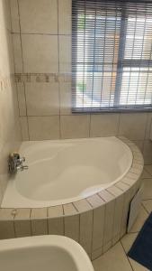 a bath tub in a bathroom with a toilet at Homes by Palesa in Maseru