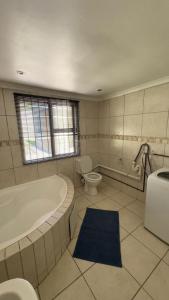 a bathroom with a tub and a toilet and a sink at Homes by Palesa in Maseru