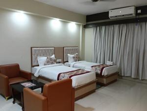 a hotel room with two beds and a chair at Hotel Star Bodh Gaya in Bodh Gaya +36 photos