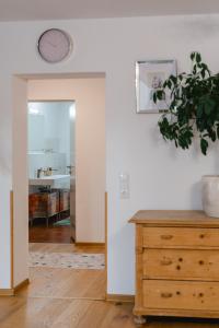 une chambre avec une horloge sur le mur et une commode en bois dans l'établissement Ferienwohnung Jelen - Kaffee - Tee - Lichthof - 135 qm, à Kolbermoor